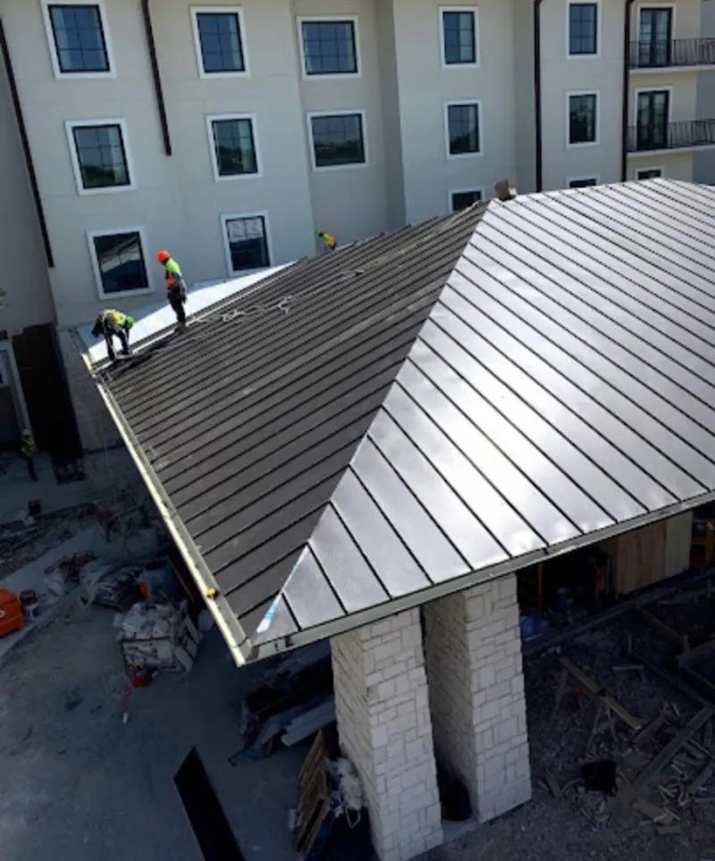 Crew installing standing seam metal roof panels on a commercial project in Valparaiso